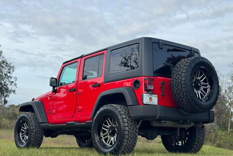 A red Jeep with custom wheels and tires