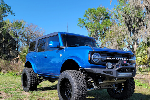 A blue Ford Bronco decked out with custom wheels and tires