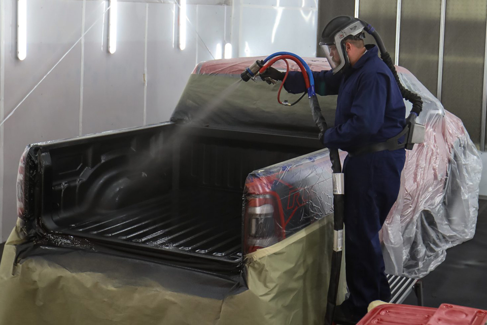 A technician spraying in a Patriot truck bed liner